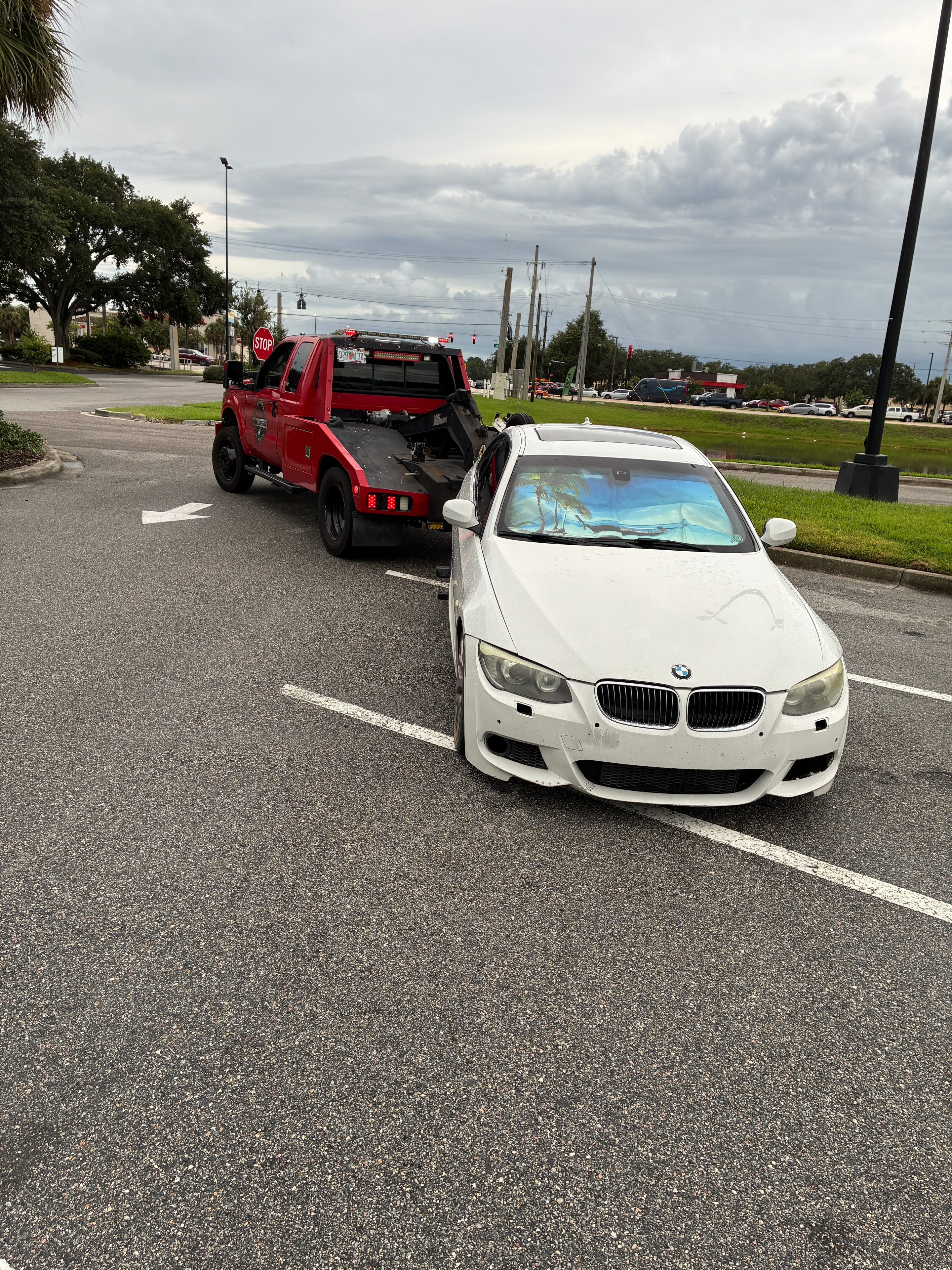 White BMW being towed by red truck