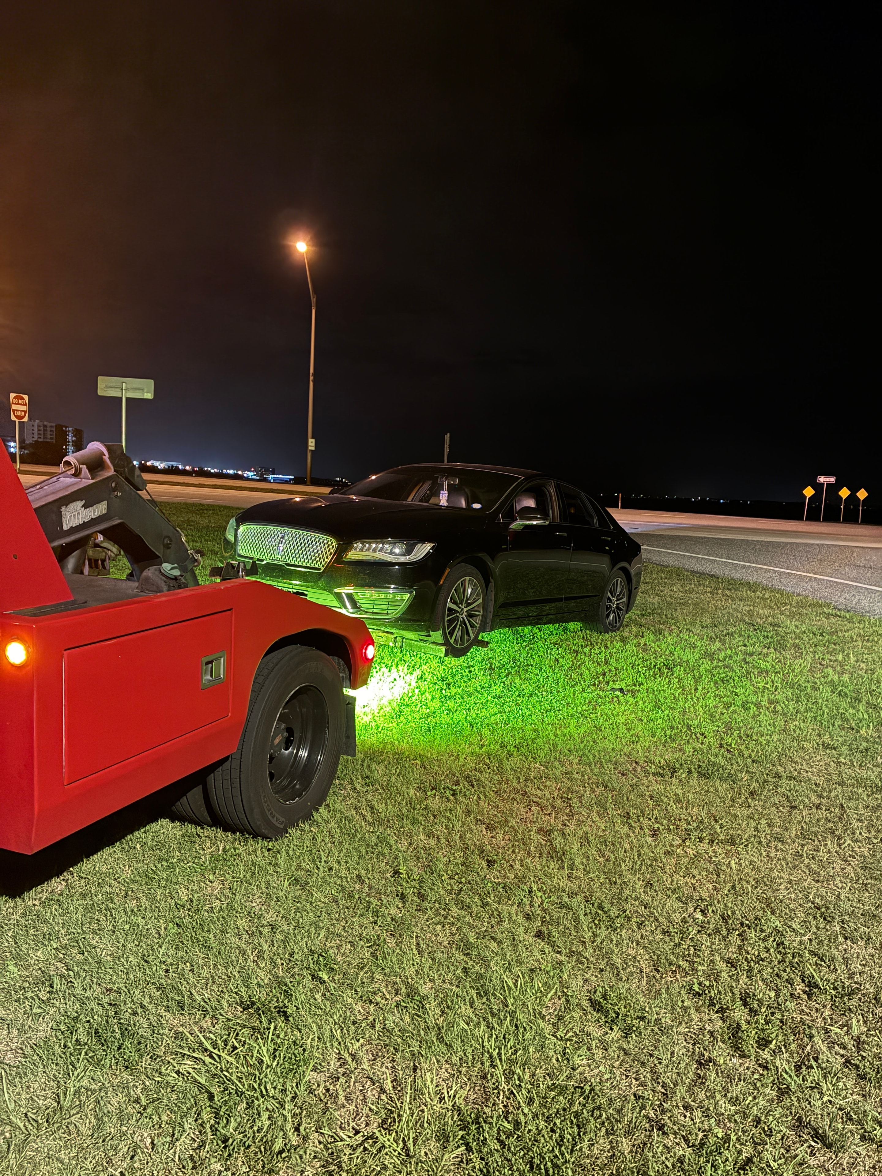 Tow truck towing black sedan at night